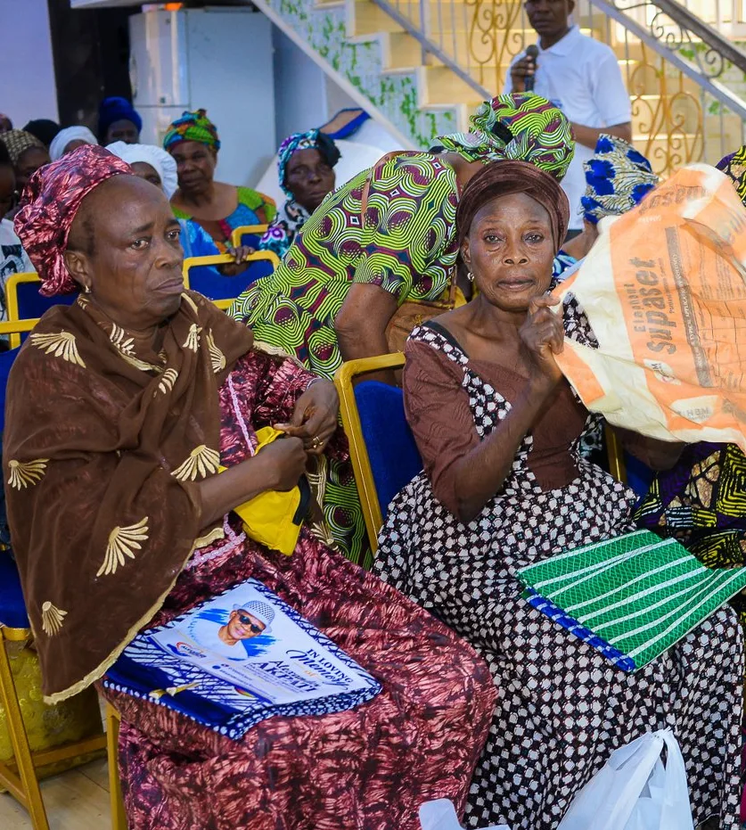 Two older women sit with the gifts they received at the Foundation’s widows’ outreach in Akute.