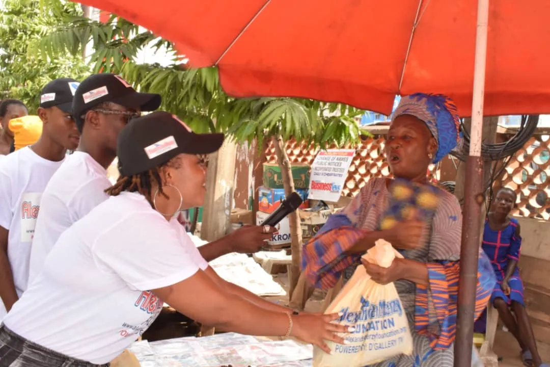 Volunteers in Foundation caps handing a gift bag to a market trader.