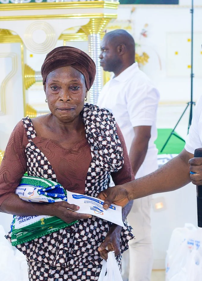 A member of the Foundation team hands a gift to a widow at the outreach in Akute.